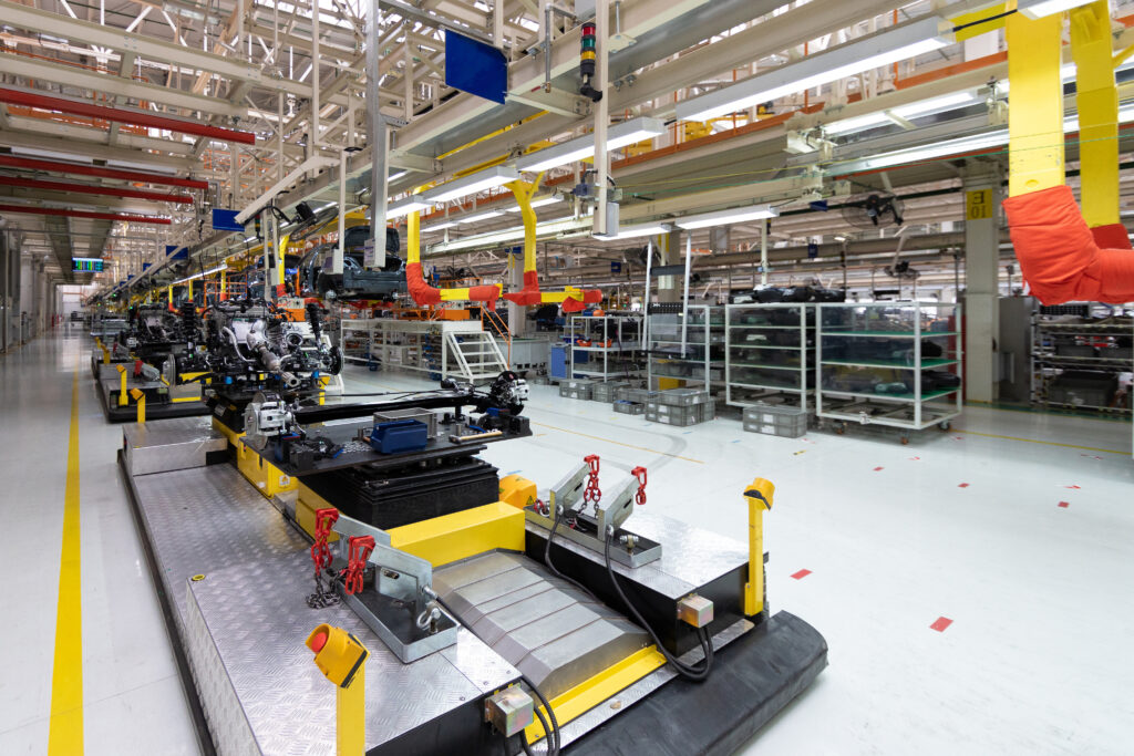 Futuristische Fabrikhalle mit Montagebändern und Robotern für die Automobilproduktion. Helle, moderne Umgebung.