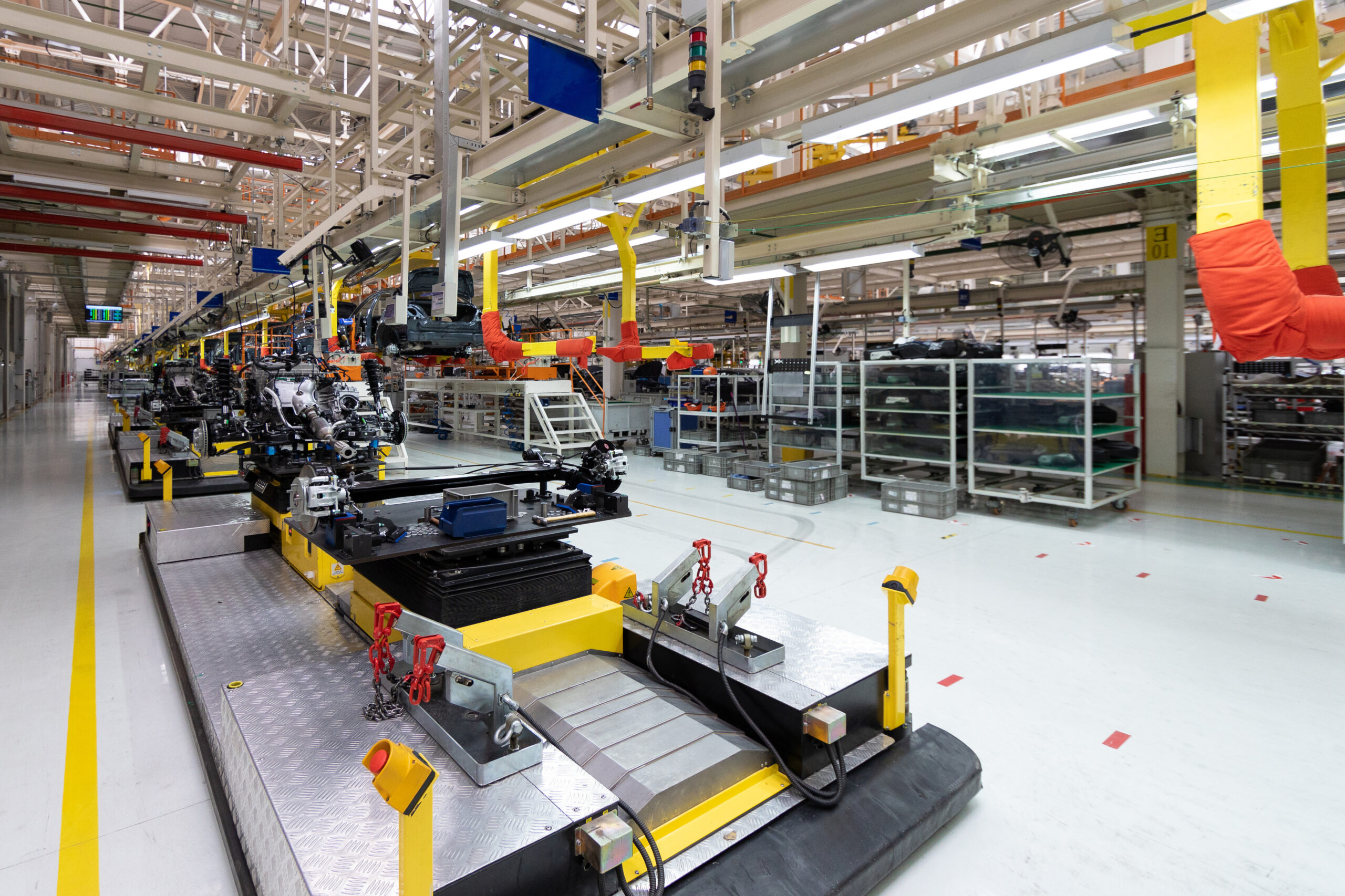 Futuristische Fabrikhalle mit Montagebändern und Robotern für die Automobilproduktion. Helle, moderne Umgebung.